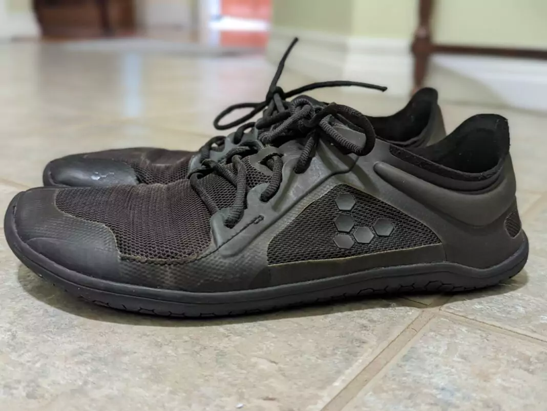 Side view of worn, black minimalist shoes