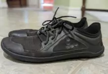 Side view of worn, black minimalist shoes