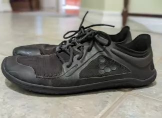 Side view of worn, black minimalist shoes